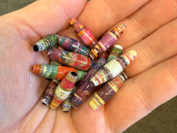A hand full of beads that are made from magazine pages