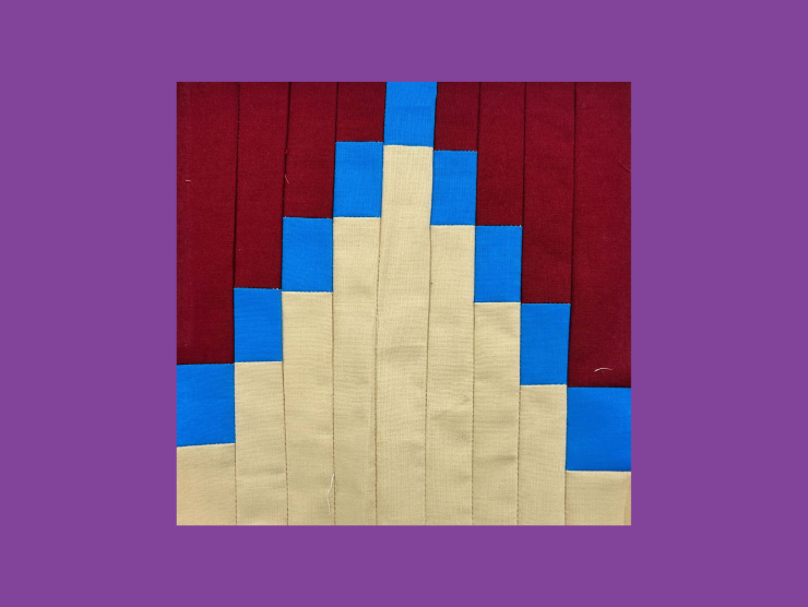 A purple background with a quilt block in front. The block has a tan triangle made of small rectangular strips protruding from the bottom. The tan strips have small blue blocks on the end, and the rest of the square is filled with red strips.