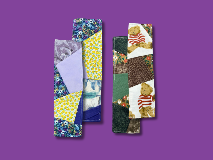 A purple background with four fabric bookmarks, the bookmarks are quilted together with various scrap fabrics